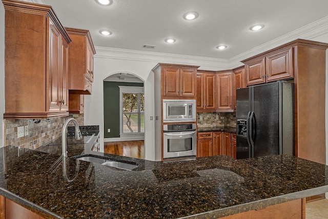 2207 Byrnewood, Jonesboro, AR 72404 - kitchen featuring appliances with stainless steel finishes, arched walkways, crown molding, a sink, and a peninsula