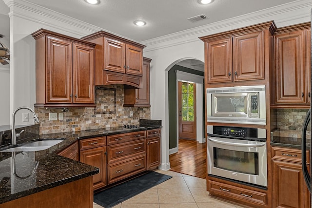 2207 Byrnewood, Jonesboro, AR 72404 - kitchen with appliances with stainless steel finishes, a sink, light tile patterned floors, arched walkways, and backsplash