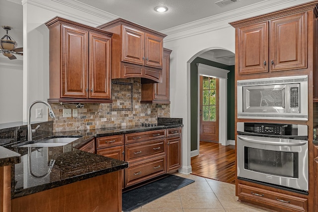 2207 Byrnewood, Jonesboro, AR 72404 - kitchen with appliances with stainless steel finishes, a sink, crown molding, light tile patterned floors, and arched walkways