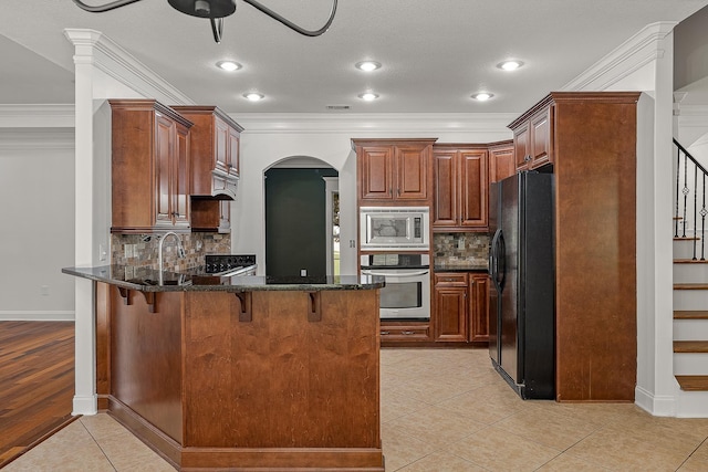 2207 Byrnewood, Jonesboro, AR 72404 - kitchen with stainless steel appliances, a peninsula, arched walkways, a breakfast bar area, and dark stone counters