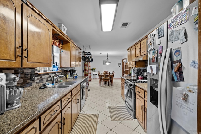 16 Clinton Ct, Cabot, AR 72023 - kitchen with appliances with stainless steel finishes, a sink, under cabinet range hood, decorative backsplash, and brown cabinetry