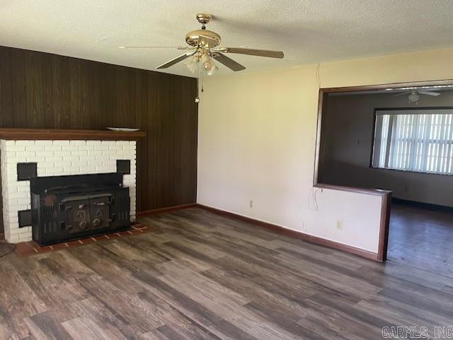 1995 Rosebud Rd, Quitman, AR 72131 - unfurnished living room with a ceiling fan, wood finished floors, baseboards, a textured ceiling, and a fireplace