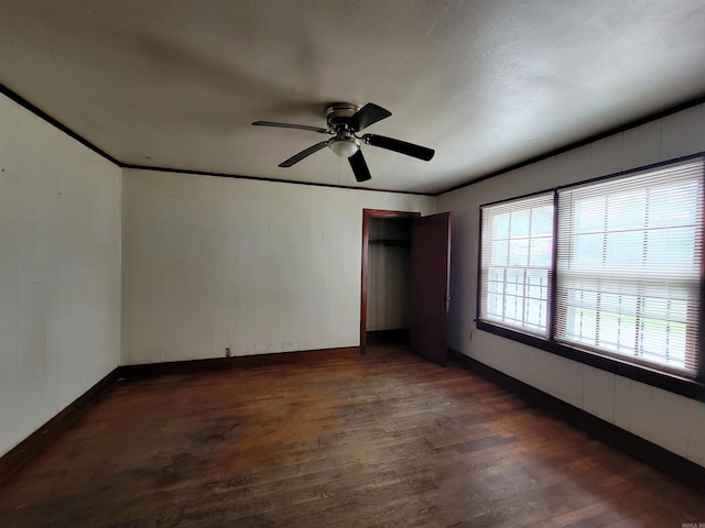 1930 S Olive, Pine Bluff, AR 71603 - unfurnished bedroom featuring dark wood-type flooring, baseboards, a ceiling fan, a closet, and wood walls