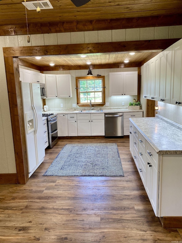 5867 County Road 4160, Ozark, AR 72949 - kitchen with stainless steel appliances, a sink, dark wood-style flooring, white cabinetry, and wood ceiling with exposed beams