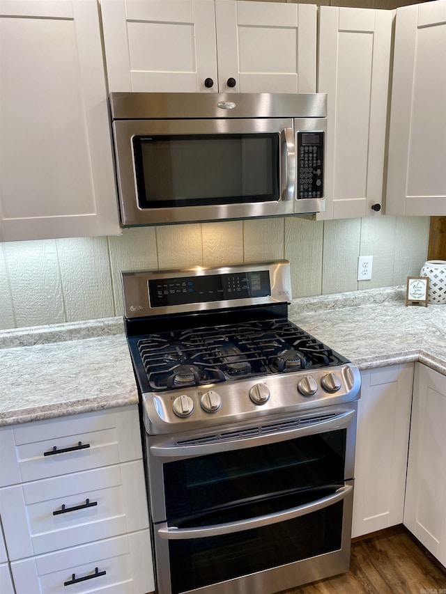 5867 County Road 4160, Ozark, AR 72949 - kitchen featuring stainless steel appliances, white cabinetry, dark wood finished floors, and tasteful backsplash