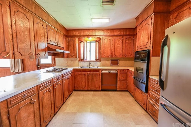 1706 W Block St, El Dorado, AR 71730 - kitchen featuring appliances with stainless steel finishes, a sink, under cabinet range hood, a warming drawer, and brown cabinets