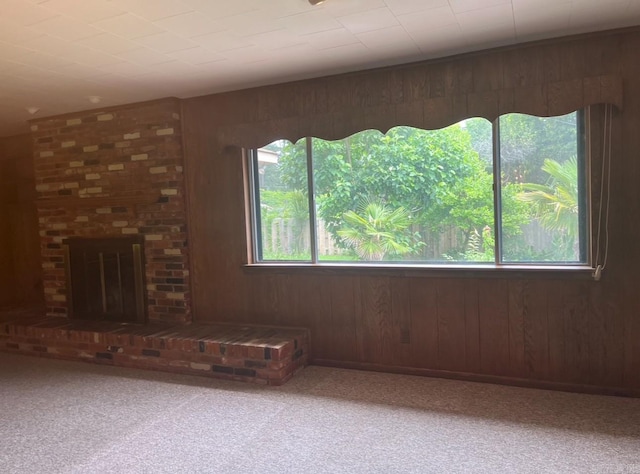 1706 W Block St, El Dorado, AR 71730 - unfurnished living room with wooden walls, a fireplace, and carpet floors