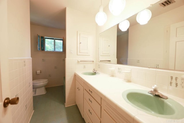 1706 W Block St, El Dorado, AR 71730 - full bathroom with tile walls, tile patterned floors, toilet, double vanity, and wainscoting