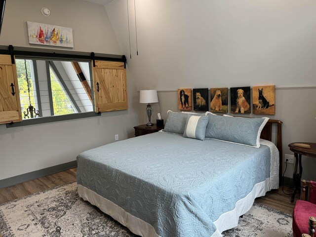 51 Yosemite Dr, Cherokee Village, AR 72529 - bedroom with wood finished floors, a barn door, baseboards, and lofted ceiling