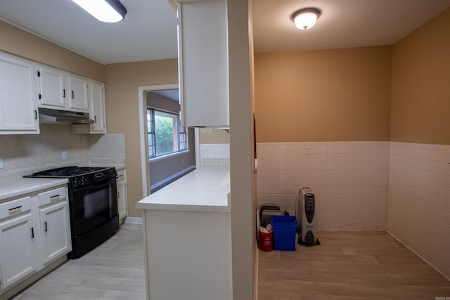 kitchen with black range with gas cooktop, under cabinet range hood, white cabinetry, light countertops, and light wood finished floors