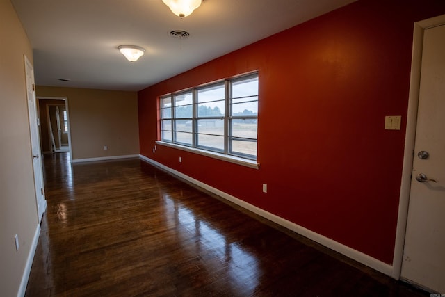 empty room featuring dark wood finished floors and baseboards