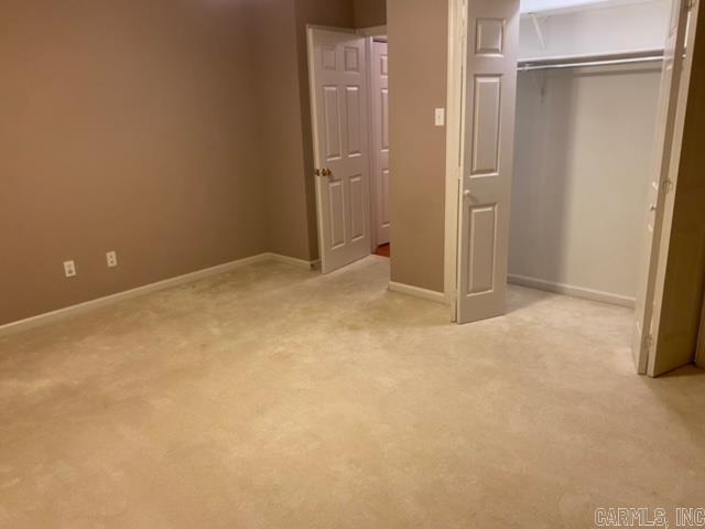 unfurnished bedroom with light colored carpet, a closet, and baseboards