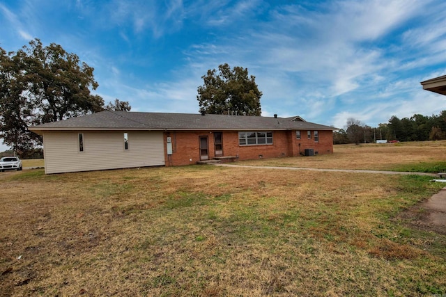 ranch-style house with a front lawn, central AC, and brick siding