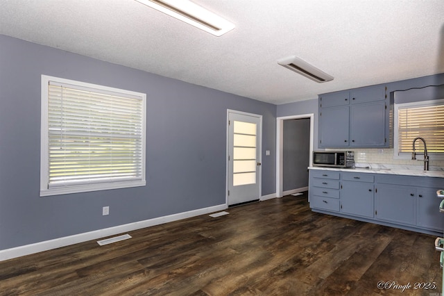 46 Hillcrest Rd, Mammoth Spring, AR 72554 - kitchen featuring stainless steel microwave, a sink, backsplash, dark wood-type flooring, and light countertops