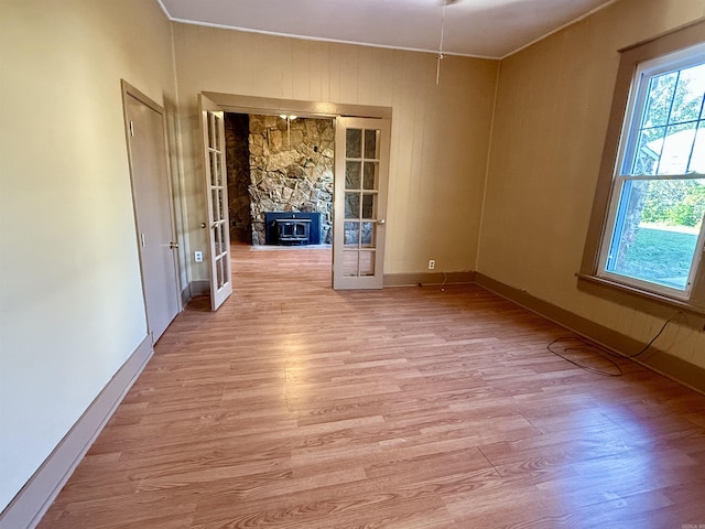 spare room featuring french doors, light wood finished floors, baseboards, and crown molding