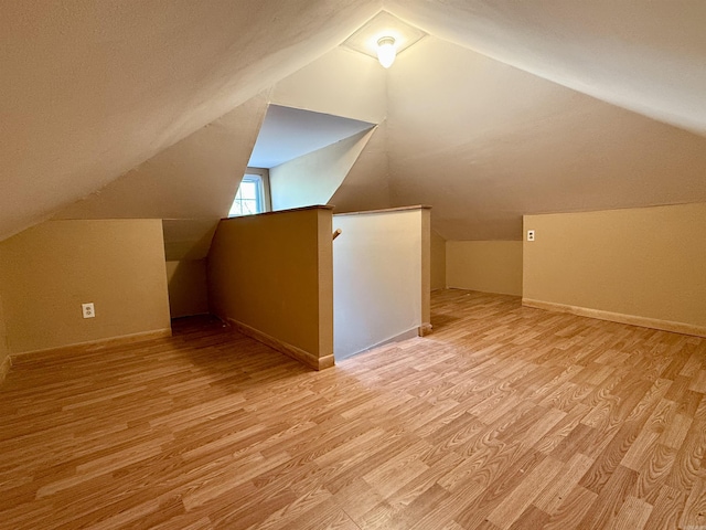 additional living space featuring light wood finished floors, lofted ceiling, and baseboards