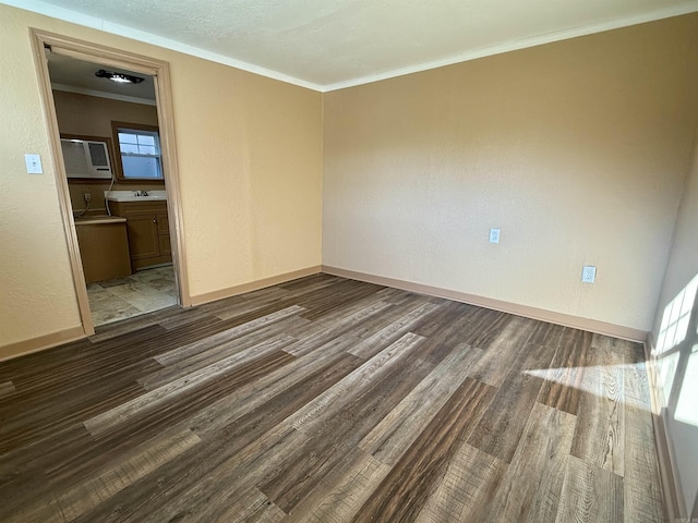 unfurnished room with wood finished floors, crown molding, baseboards, and a textured wall