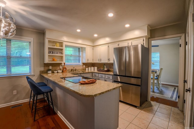 2318 Breckenridge Dr, Little Rock, AR 72227 - kitchen featuring freestanding refrigerator, a peninsula, white cabinetry, ornamental molding, and plenty of natural light