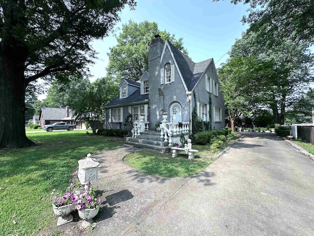 582 N Fourth Ave, Piggott, AR 72454 - english style home with a chimney, a front yard, and driveway