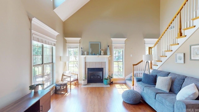 3805 Irby Dr, Conway, AR 72034 - living room with a towering ceiling, stairway, wood finished floors, a tiled fireplace, and baseboards