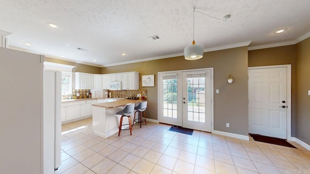 3805 Irby Dr, Conway, AR 72034 - kitchen with white appliances, a breakfast bar area, a peninsula, white cabinets, and backsplash