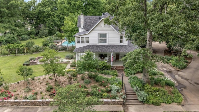 view of front of home with stairway, roof with shingles, a front yard, a chimney, and a porch