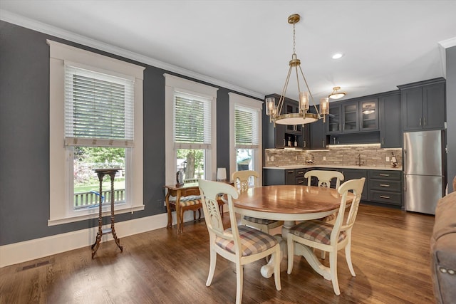 dining room featuring a chandelier, ornamental molding, dark wood-style flooring, baseboards, and recessed lighting