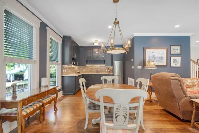 dining room with ornamental molding, a chandelier, recessed lighting, light wood-style floors, and baseboards