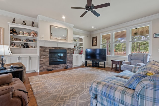 living room featuring ornamental molding, wood finished floors, ceiling fan, a glass covered fireplace, and recessed lighting