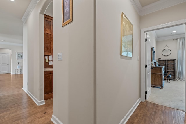 hall featuring arched walkways, wood finished floors, ornamental molding, and baseboards