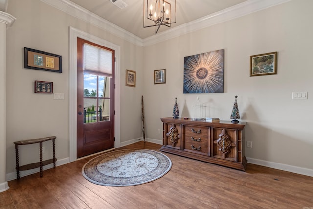 entrance foyer with a chandelier, baseboards, wood finished floors, and ornamental molding