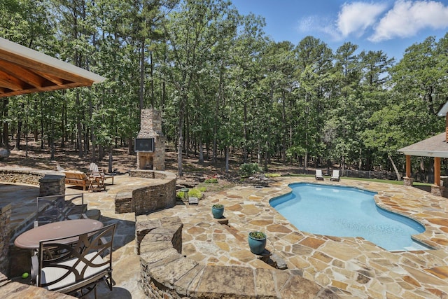13200 Bart Moreland Dr, Roland, AR 72135 - swimming pool featuring a stone fireplace, a patio, and view of wooded area