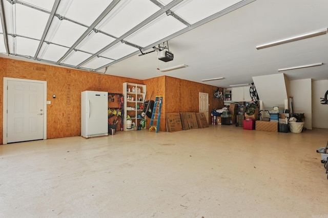 13200 Bart Moreland Dr, Roland, AR 72135 - garage featuring freestanding refrigerator, a garage door opener, and wood walls