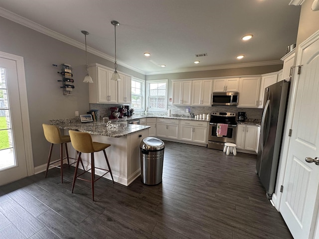 1008 Wildcat Ln, Jonesboro, AR 72405 - kitchen with appliances with stainless steel finishes, a peninsula, backsplash, white cabinetry, and stone counters