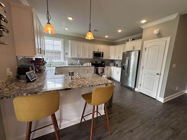 1008 Wildcat Ln, Jonesboro, AR 72405 - kitchen featuring appliances with stainless steel finishes, a peninsula, crown molding, decorative backsplash, and light stone countertops