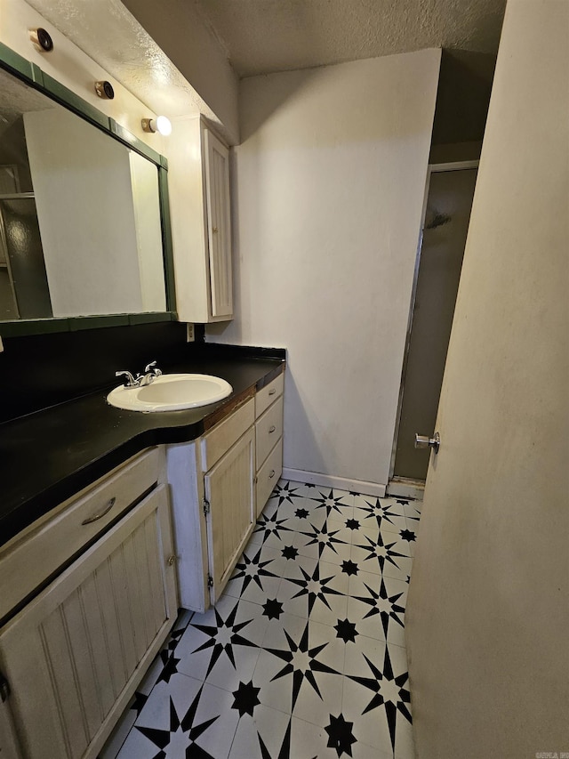 1421 W 25th St, North Little Rock, AR 72114 - bathroom featuring vanity, tile patterned floors, a stall shower, a textured ceiling, and baseboards