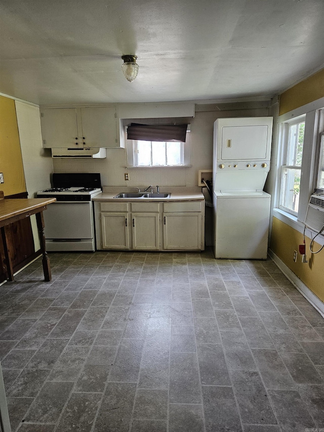 1421 W 25th St, North Little Rock, AR 72114 - kitchen with white range with gas cooktop, stacked washing machine and dryer, a sink, extractor fan, and cream cabinetry