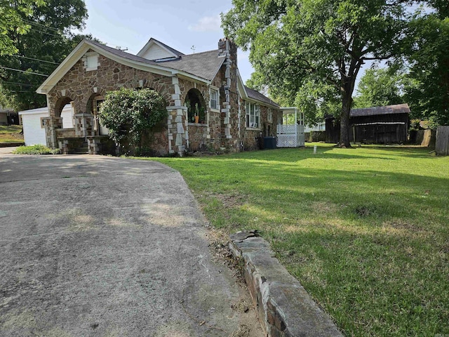 1421 W 25th St, North Little Rock, AR 72114 - view of home's exterior with stone siding, a chimney, and driveway