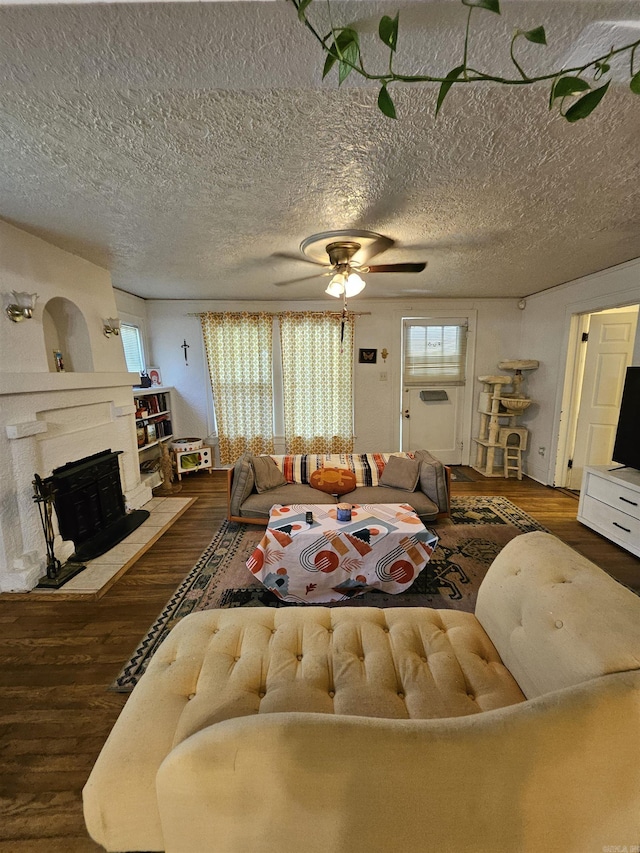 1421 W 25th St, North Little Rock, AR 72114 - living room with wood finished floors, a fireplace with raised hearth, a ceiling fan, and a textured ceiling
