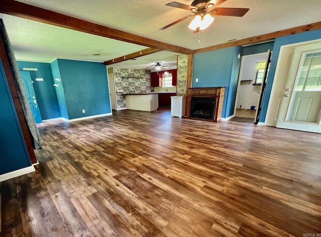 470 Lr 28, Foreman, AR 71836 - unfurnished living room featuring a ceiling fan, a fireplace, a textured ceiling, dark wood finished floors, and baseboards
