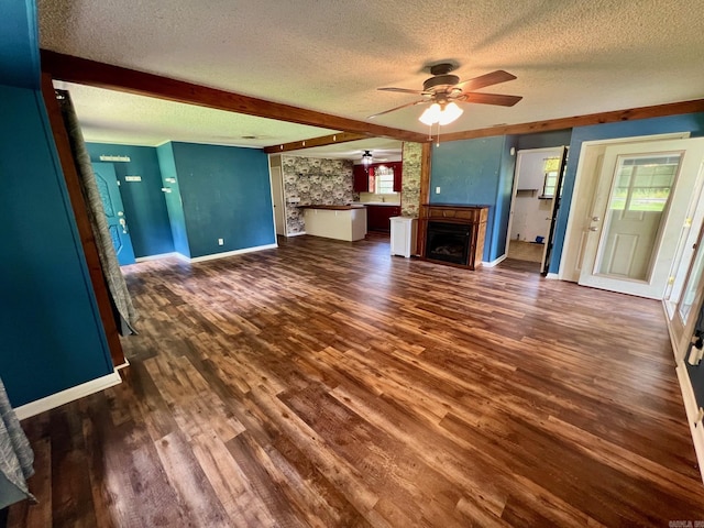 470 Lr 28, Foreman, AR 71836 - unfurnished living room with a ceiling fan, a textured ceiling, a fireplace, dark wood finished floors, and baseboards