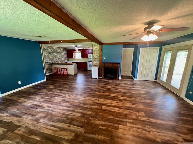 470 Lr 28, Foreman, AR 71836 - unfurnished living room featuring a ceiling fan, a textured ceiling, dark wood-type flooring, baseboards, and a fireplace