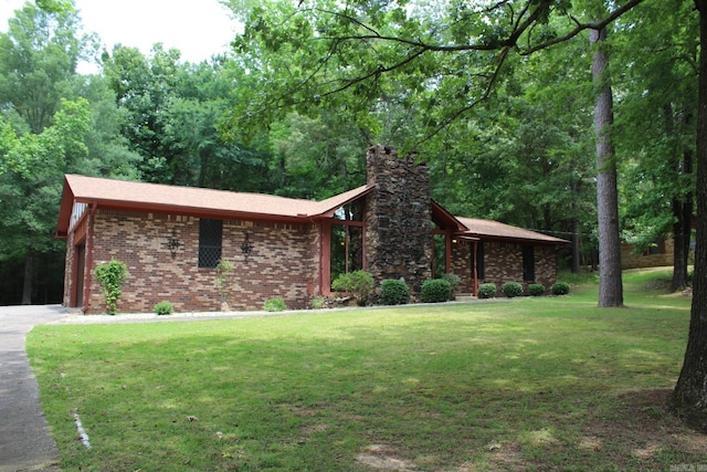 108 Charles St, Murfreesboro, AR 71958 - view of front facade featuring a chimney, brick siding, a front lawn, an attached garage, and driveway