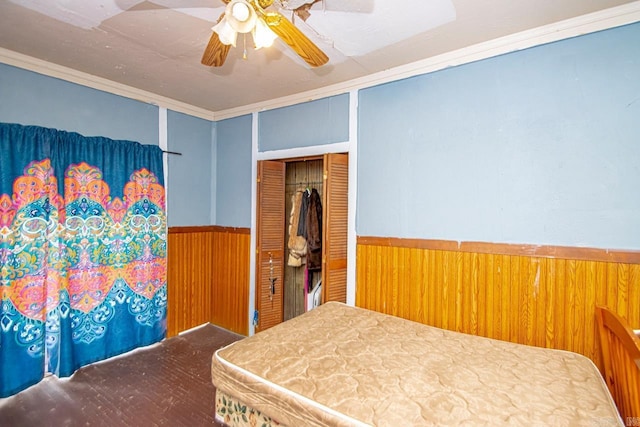 331 N Park St, Little Rock, AR 72205 - bedroom with wainscoting, wood walls, a ceiling fan, a closet, and ornamental molding