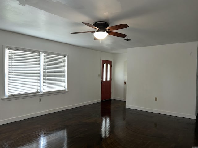 unfurnished living room featuring ceiling fan, baseboards, and dark wood-type flooring
