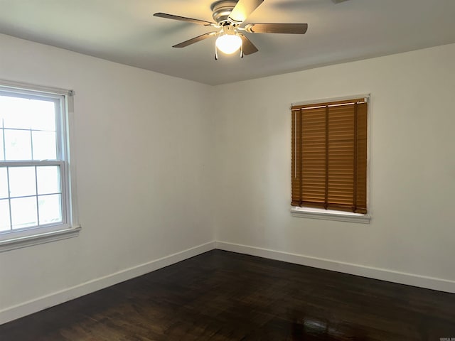 spare room with baseboards, a ceiling fan, and dark wood finished floors