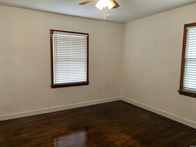 spare room featuring dark wood-style flooring, baseboards, and a ceiling fan