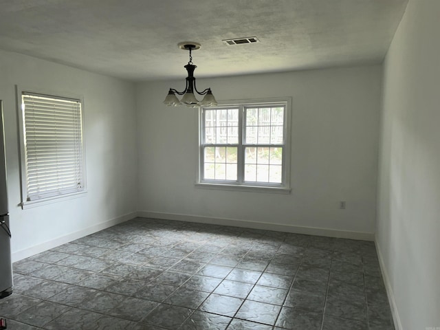 unfurnished room featuring a chandelier, baseboards, and dark stone finish floors