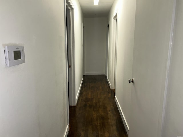 corridor with dark wood finished floors and baseboards