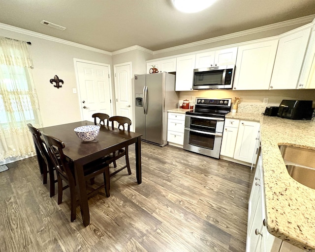 135 Meadow Dr, Beebe, AR 72012 - kitchen featuring stainless steel appliances, ornamental molding, dark wood-type flooring, white cabinetry, and light stone counters